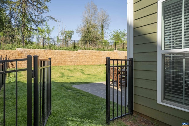 view of gate with a lawn and a fenced backyard
