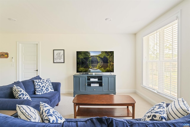 living room featuring baseboards, plenty of natural light, and light carpet