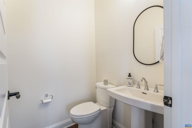 bathroom with a sink, baseboards, and toilet