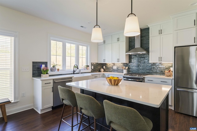 kitchen featuring decorative backsplash, a center island, a sink, dark wood finished floors, and appliances with stainless steel finishes