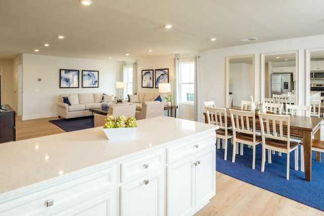 kitchen featuring white cabinetry, stainless steel appliances, light hardwood / wood-style floors, and light stone counters