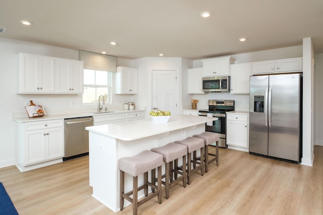 kitchen with sink, a breakfast bar area, white cabinetry, appliances with stainless steel finishes, and a kitchen island