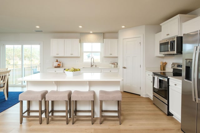 kitchen with stainless steel appliances, a center island, sink, and white cabinets