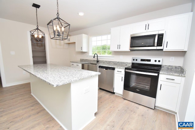 kitchen with sink, appliances with stainless steel finishes, white cabinetry, a kitchen island, and decorative light fixtures