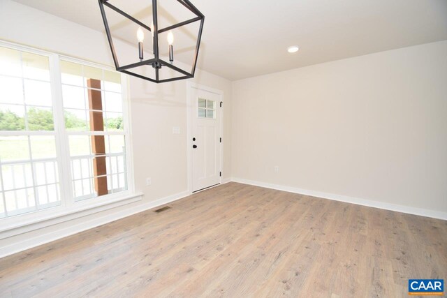 unfurnished dining area featuring light hardwood / wood-style flooring, a notable chandelier, and plenty of natural light