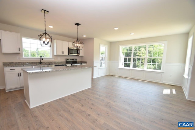 kitchen featuring sink, white cabinetry, decorative light fixtures, a center island, and stainless steel appliances