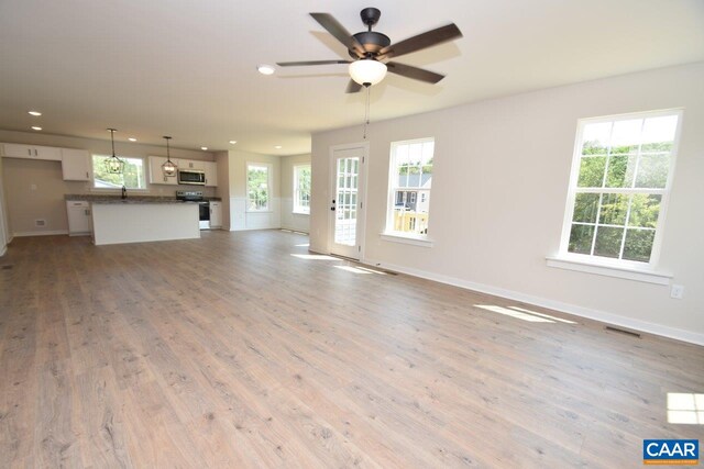 unfurnished living room featuring ceiling fan, sink, and light hardwood / wood-style floors