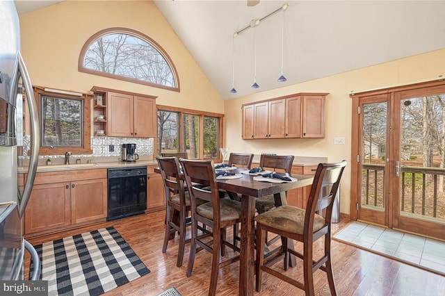 dining room featuring high vaulted ceiling, light wood-type flooring, and track lighting