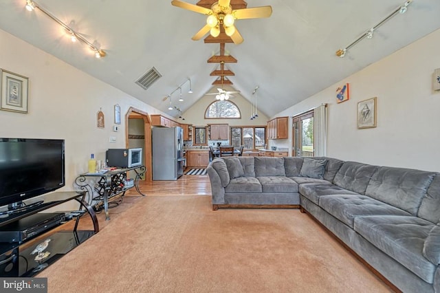 living area featuring light carpet, visible vents, lofted ceiling, ceiling fan, and track lighting