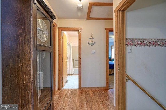 corridor with baseboards and light wood-style floors