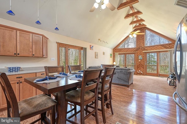 dining area with high vaulted ceiling, visible vents, a ceiling fan, light wood finished floors, and beamed ceiling