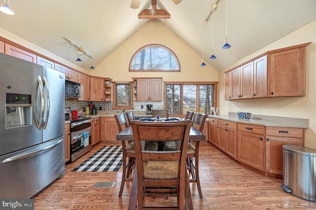 kitchen with light wood finished floors, tasteful backsplash, appliances with stainless steel finishes, and open shelves