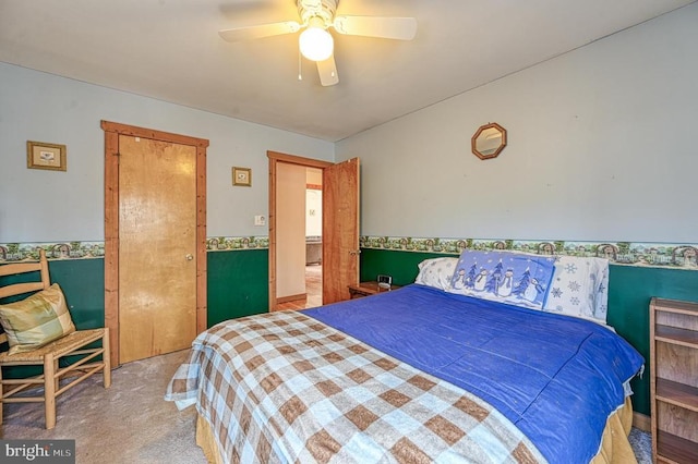 bedroom with carpet floors, a wainscoted wall, and ceiling fan