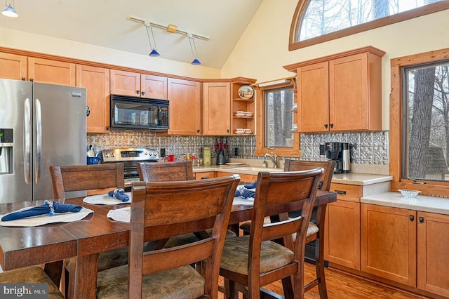 kitchen featuring open shelves, stainless steel appliances, tasteful backsplash, light countertops, and light wood-style flooring