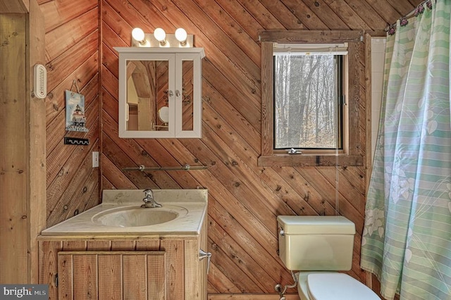 bathroom featuring curtained shower, wood walls, vanity, and toilet