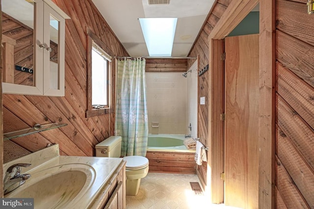 full bathroom featuring toilet, wooden walls, vanity, tile patterned floors, and shower / bath combo