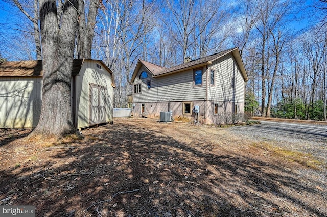 back of property featuring an outbuilding, a shed, and central air condition unit