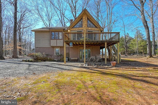 rear view of house featuring stairway, a deck, and stucco siding