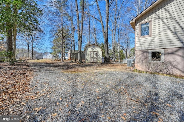 view of yard featuring central air condition unit, a storage unit, and an outdoor structure