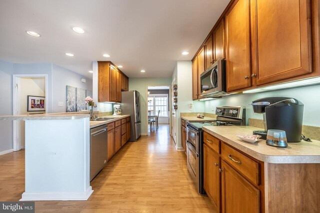 kitchen with sink, appliances with stainless steel finishes, a kitchen bar, and light hardwood / wood-style floors