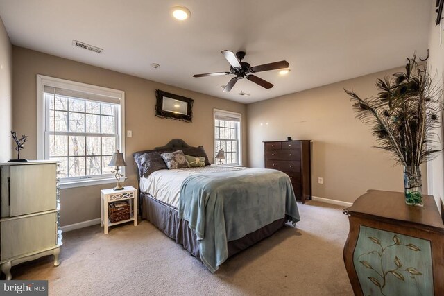 carpeted bedroom with multiple windows and ceiling fan