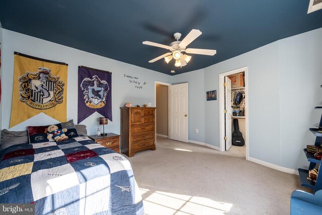 bedroom featuring a walk in closet, carpet, and ceiling fan