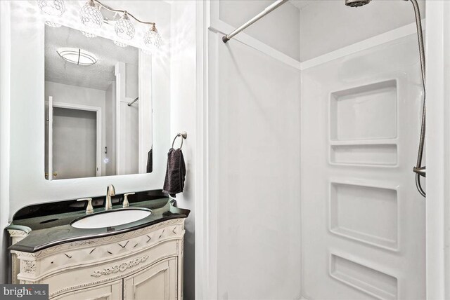 bathroom featuring vanity, a textured ceiling, and a shower