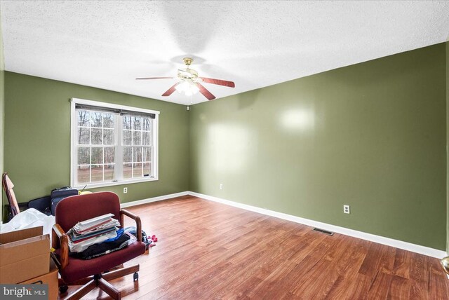 sitting room with ceiling fan, hardwood / wood-style floors, and a textured ceiling