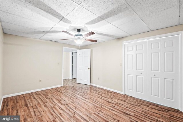 unfurnished bedroom with hardwood / wood-style flooring, a paneled ceiling, ceiling fan, and a closet