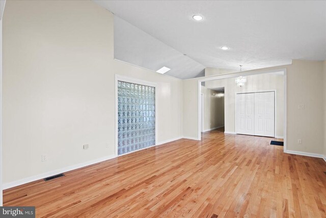 spare room featuring vaulted ceiling and light hardwood / wood-style flooring