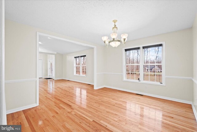 unfurnished dining area featuring an inviting chandelier and hardwood / wood-style floors