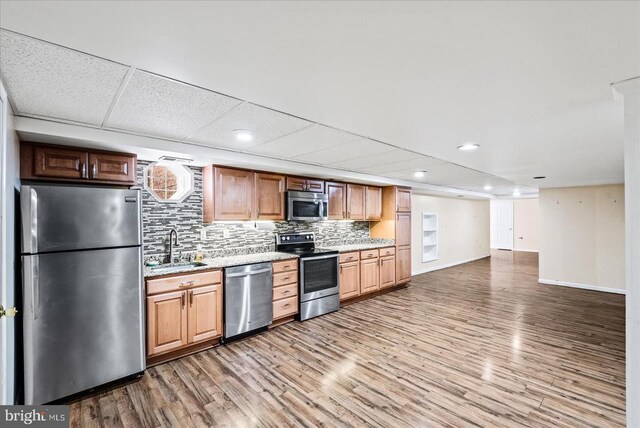 kitchen featuring stainless steel appliances, sink, wood-type flooring, and backsplash