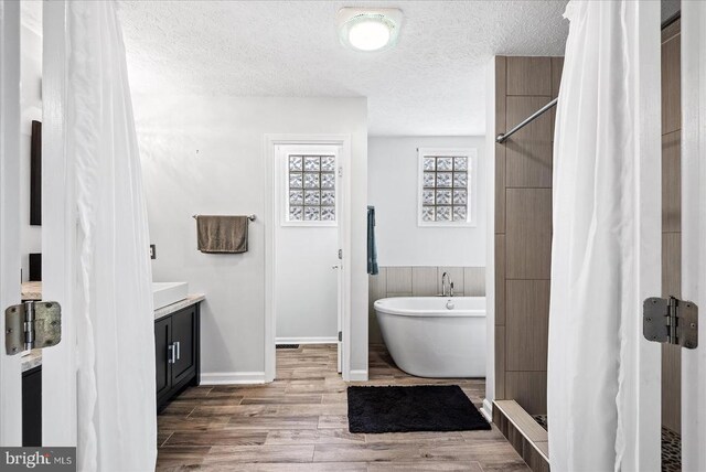 bathroom featuring vanity, independent shower and bath, wood-type flooring, and a textured ceiling