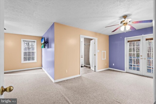 spare room featuring light carpet, ceiling fan, french doors, and a textured ceiling