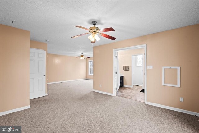 carpeted spare room with ceiling fan, a healthy amount of sunlight, and a textured ceiling