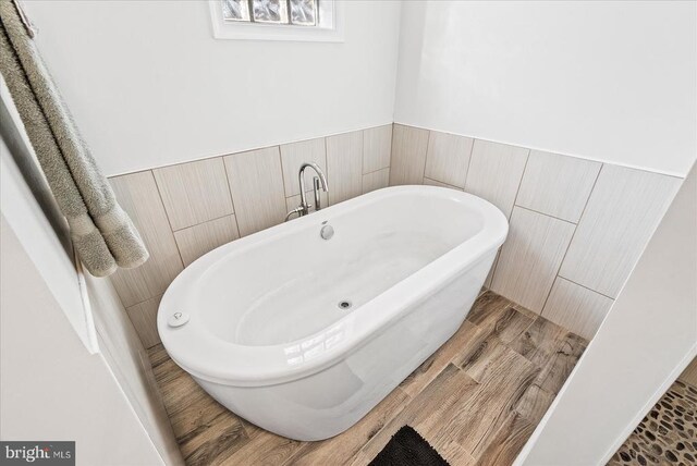 bathroom with hardwood / wood-style floors and a tub