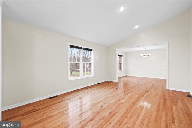 unfurnished room with a notable chandelier, vaulted ceiling, and light wood-type flooring