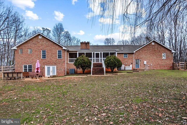 back of house featuring a yard, a patio area, and a sunroom