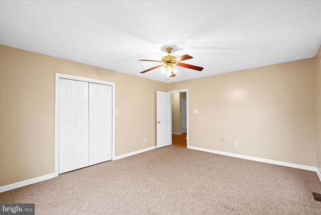 unfurnished bedroom with ceiling fan, carpet flooring, a closet, and a textured ceiling