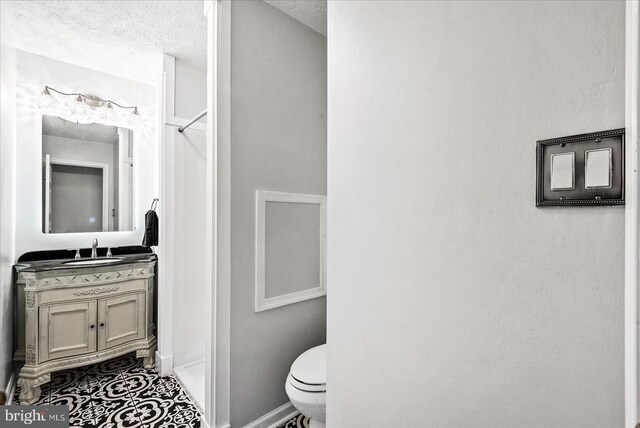 bathroom with vanity, walk in shower, a textured ceiling, and toilet