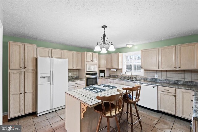 kitchen with pendant lighting, sink, white appliances, tasteful backsplash, and a kitchen island