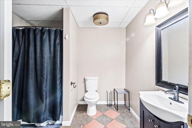 bathroom featuring vanity, toilet, curtained shower, and a drop ceiling