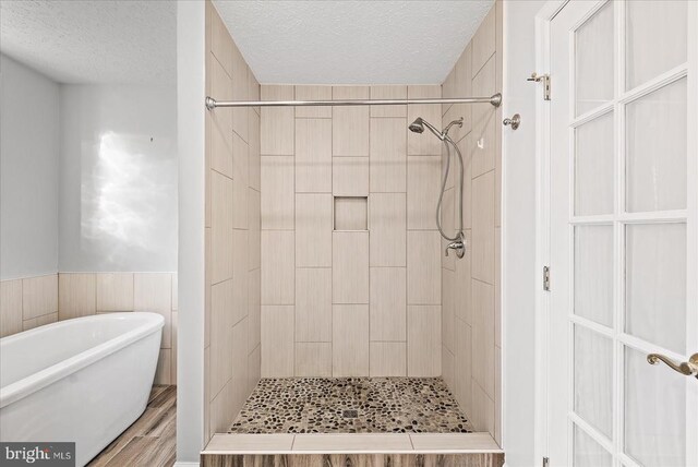 bathroom with separate shower and tub, hardwood / wood-style floors, and a textured ceiling