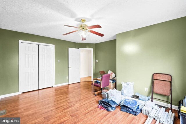 interior space with a textured ceiling, ceiling fan, and light wood-type flooring