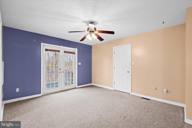 carpeted empty room with ceiling fan, a textured ceiling, and french doors