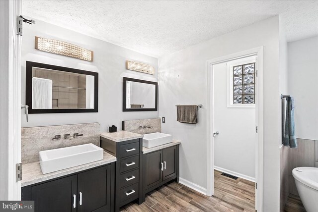 bathroom with hardwood / wood-style flooring, vanity, a textured ceiling, and a tub