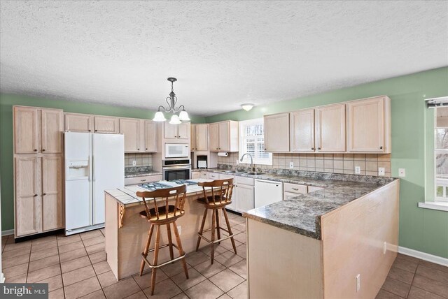 kitchen with sink, a breakfast bar area, tasteful backsplash, decorative light fixtures, and white appliances