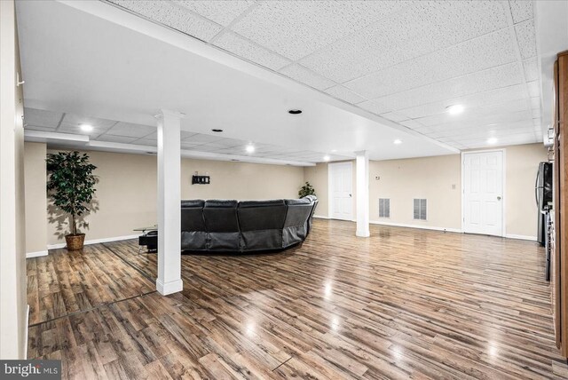 living room featuring decorative columns, hardwood / wood-style floors, and a drop ceiling