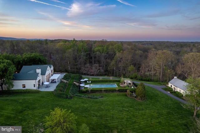 aerial view at dusk featuring a view of trees