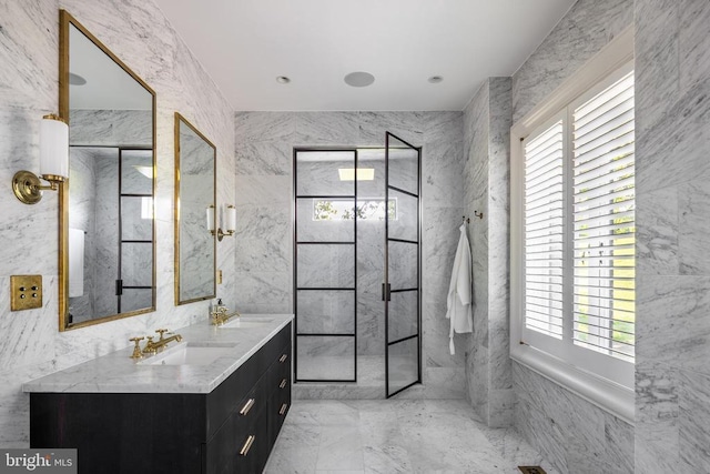 full bath featuring walk in shower, marble finish floor, tile walls, and vanity